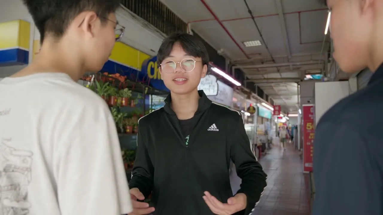 Three boys talk in a covered corridor lined with shops